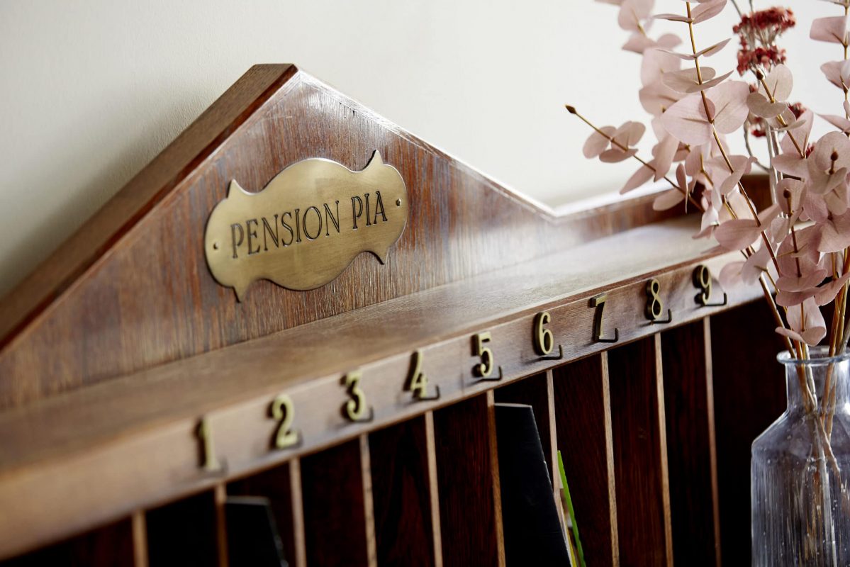 Auf diesem Bild ist ein Schlüsselbrett mit der Aufschrift "Pension Pia" zu sehen.