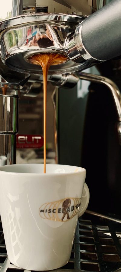 Auf diesem Bild ist zu sehen wie frischer Kaffee von einer Kaffeemaschine in eine Kaffeetasse fließt.